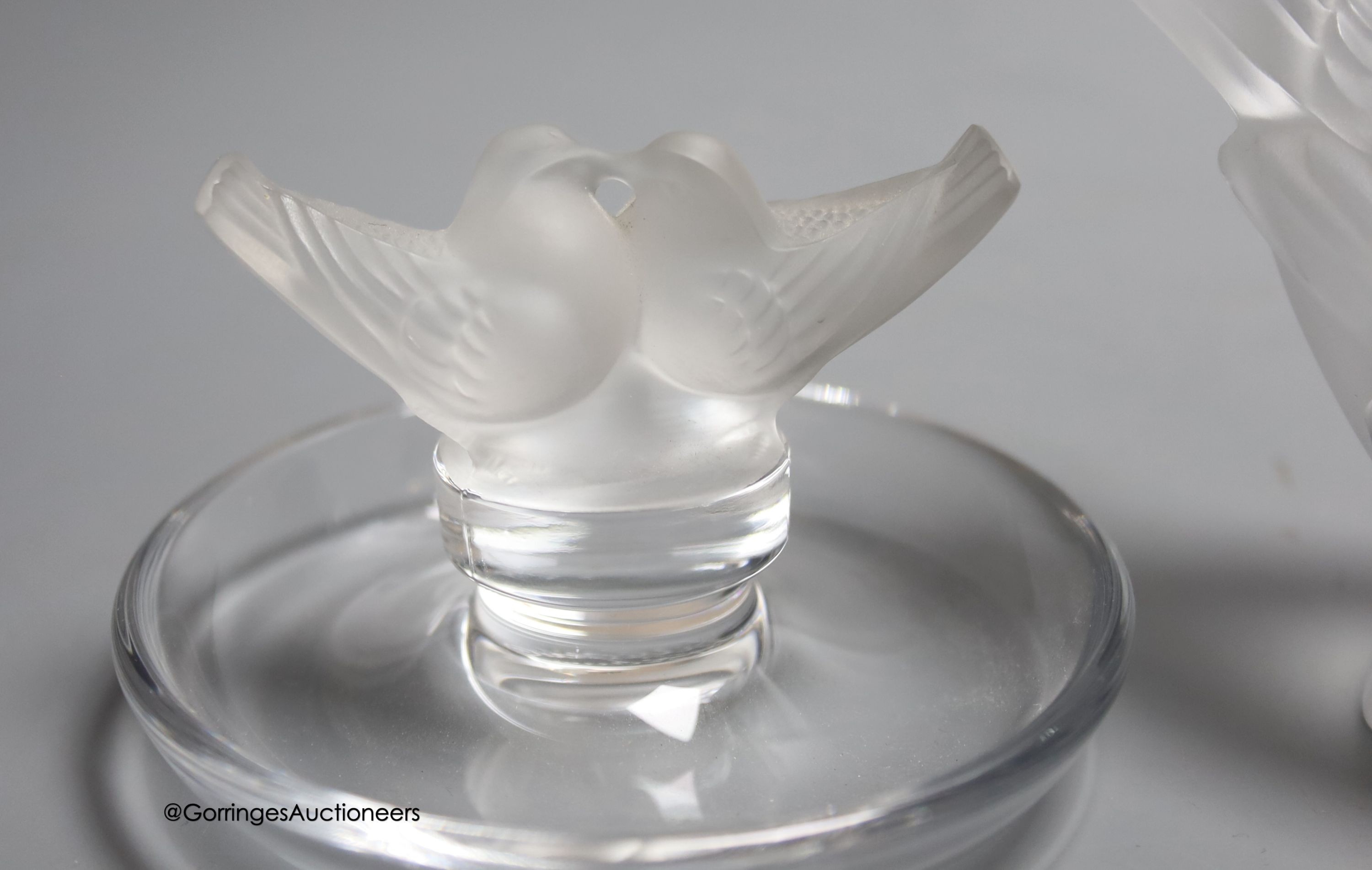 Two Lalique ashtrays mounted with birds, etched signatures to bases, and a Lalique style frosted glass bird paperweight